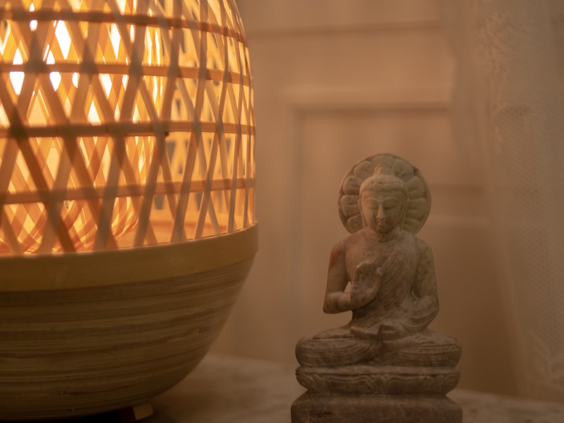 Lampe en osier allumée et statuette de bouddha en pierre